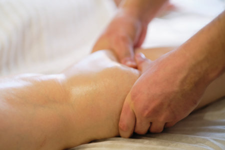 Detail of hands massaging human calf muscle.Therapist applying pressure on female leg. Hands of massage therapist massaging legs of young woman in spa salon. Body care in spa salon for young woman.の写真素材