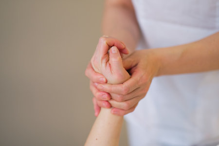 Wrist massage. massage therapist puts pressure on a sensitive point on a womans hand. Physiotherapist massaging her patients hand in medical officeの写真素材