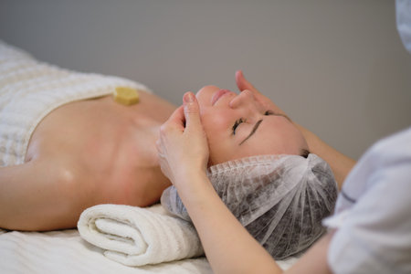 Beautiful girl has a facial massage in a beauty clinic. skin care, spa concept, treatment. Face massage. Facial skincare. Hands of masseur. Woman at beauty spa salon.の写真素材