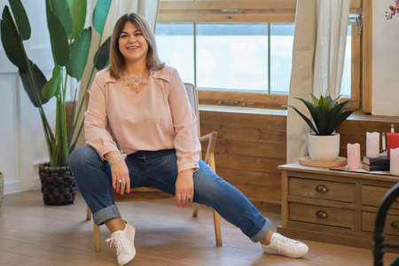 self-sufficient confident middle-aged woman. sitting on a chair in a confident posture. concept of self-acceptanceの写真素材
