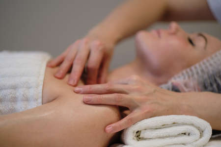 Beautiful girl has a facial massage in a beauty clinic. skin care, spa concept, treatment. Face massage. Facial skincare. Hands of masseur. Woman at beauty spa salon.の写真素材