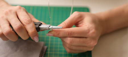 Woman using pliers to adjust malachite gemstones. Craft jewelery making with professional tools. A handmade jeweler process, manufacture of jewellery.の写真素材