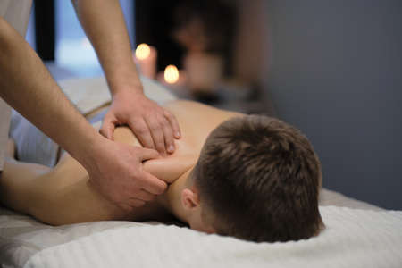 Close-up of man enjoying in relaxing shoulders massage . Man relaxing on massage table receiving massageの写真素材