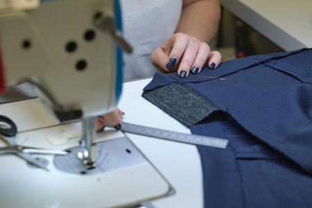 seamstress workplace. Woman seamstress makes pattern with chalk on fabric for sewing clothes in...