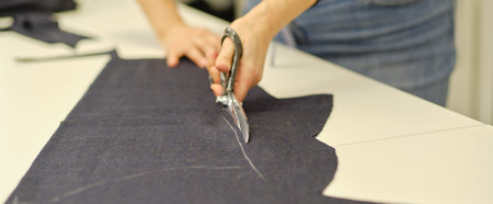 Dressmaker cutting dress fabric on sketch line. Fashion designer tailor or sewer in workshop studio...