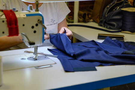 seamstress workplace. Woman seamstress makes pattern with chalk on fabric for sewing clothes in...