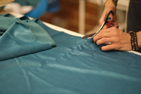 Dressmaker cutting dress fabric on sketch line. Fashion designer tailor or sewer in workshop studio...