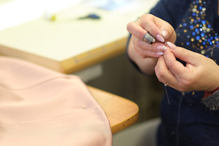 Talented female seamstress working with textile for sewing clothes. Close up view of sewing process....