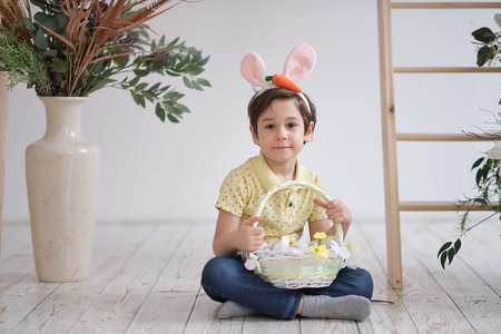 Child boy wearing bunny ears. portrait of a child sitting on the floor and holding a basket of...