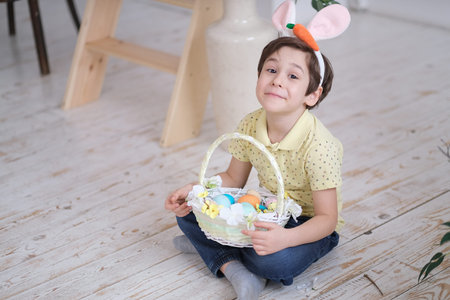 Child boy wearing bunny ears. portrait of a child sitting on the floor and holding a basket of...