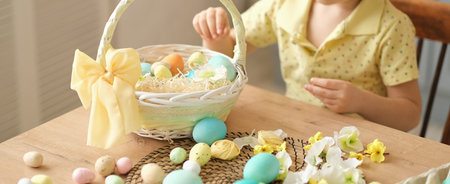 banner unrecognizable little boy puts colored eggs in a wicker Easter basket. easter preparation...