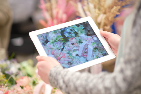 young woman entrepreneur takes pictures of his hand-made floral composition for the blog. the concept of promoting an entrepreneur on the internet.の写真素材