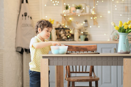 little boy puts colored eggs in a wicker Easter basket. easter preparation conceptの写真素材