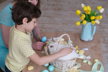 little boy stroking a white bunny, easter family fun. kids with bunny ears and mom in the kitchen...