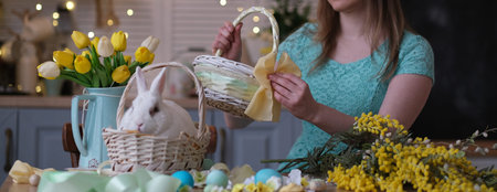 young woman decorates Easter basket in cozy kitchen interior. table kitchen with flowers, easter...