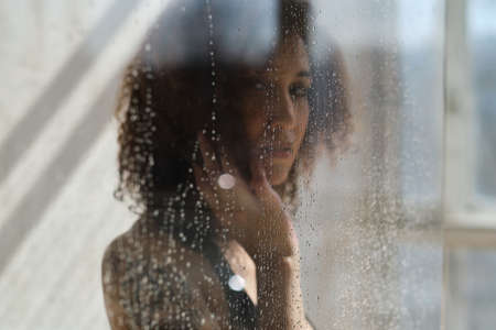 Defocused image of young female model poses in shower cabine. Peaceful woman. Soul healing. Spiritual practice. Esoteric mystery.の写真素材