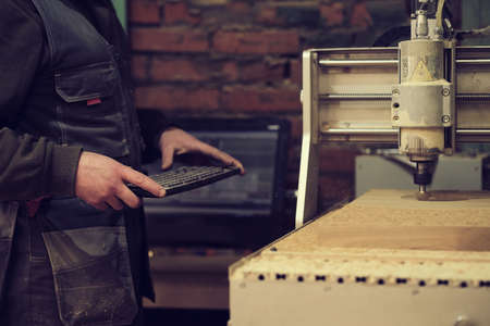 Milling a wooden board. Processing of wood panels on CNC coordinate milling woodworking machines. Slow motion video. Sawdust scatter in different directionsの写真素材