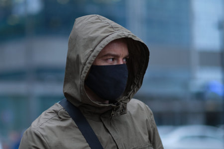 Closeup of a 35-year-old male in a respirator to protect against infection with influenza virus or coronavirus. Handsome young European man in winter clothes on the street with a medical face mask on.の写真素材