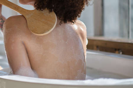Smiling and relaxing african american woman bathing in a tub full of foam. Amazing time. lifestyle people conceptの写真素材