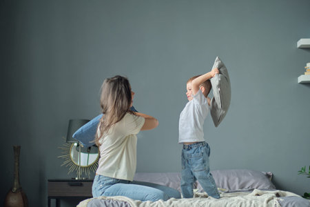 mother playing with her toddler little son on a bed together. Family moments, children care....