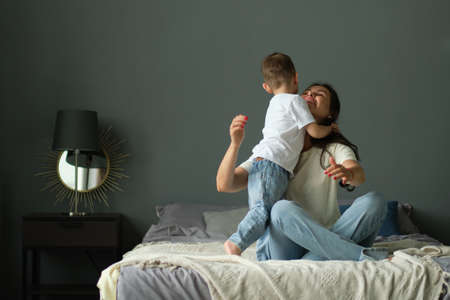 mother hugs with her toddler little son on a bed together. Family moments, children care. Motherhood, maternity leave conceptの写真素材
