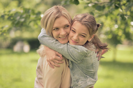 happy mother with her daughter hugging a teenager in the summer. Caring happy mother enjoy day with teenage girl child, laugh have fun. Mother giving her daughter advice.の写真素材