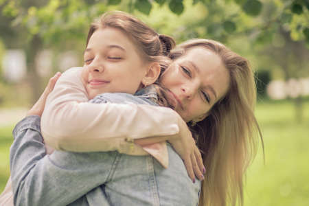 happy mother with her daughter hugging a teenager in the summer. Caring happy mother enjoy day with teenage girl child, laugh have fun. Mother giving her daughter advice.の写真素材