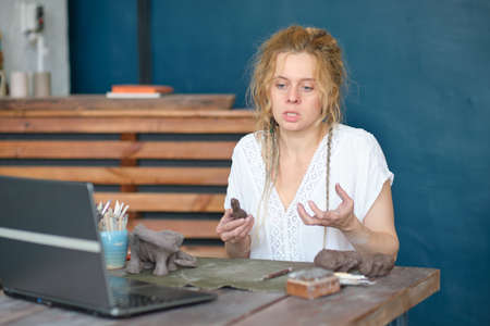 artisan pottery tutor in art studio. woman ceramist teaches an online lesson or leads a video master class on creating ceramic productsの写真素材