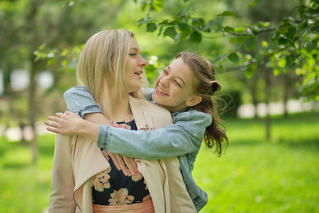 happy mother with her daughter hugging a teenager in the summer. Caring happy mother enjoy day with...