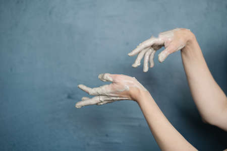 female hands clotted mud clay play cheerfully and show hands. Hands dirtyの写真素材