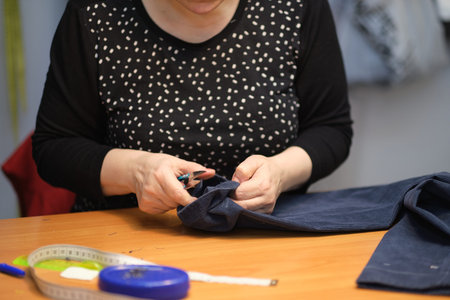 Dressmaker cutting dress fabric on sketch line. Fashion designer tailor or sewer in workshop studio designing new collection clothes. Business owner shop and entrepreneur conceptの写真素材