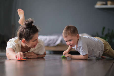Expressive baby boy playing with a toy car with mother.の写真素材