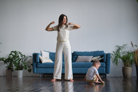 Happy mindful single mother doing morning exercises in yoga pose with kid playing at home. morning exercises in pajamas. child interferes with the workoutの写真素材