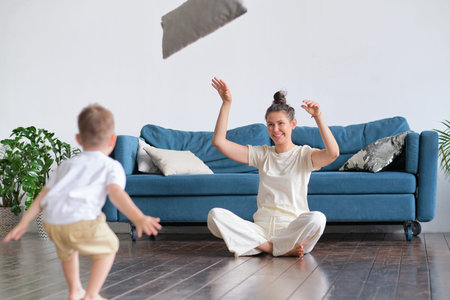 mother meditating for stress relief and emotional balance relaxing in living room with child. single...