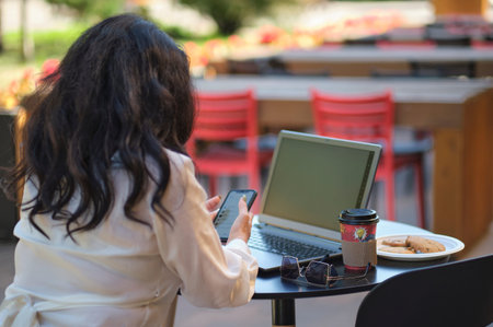 smiling mature businesswoman drinking coffee while working in cafe