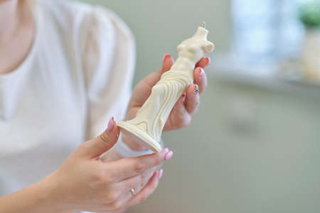 woman entrepreneur holds a ready-made candle made of beeswax in her hands. small business conceptの写真素材