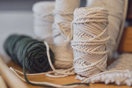 Balls of white yarn and rustic sticks on table. Good for macrame and handicrafts banners. natural decoration concept.の写真素材