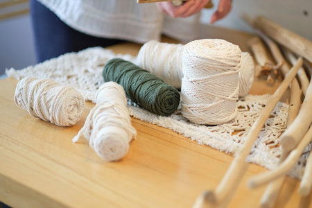 Balls of white yarn and rustic sticks on table. Good for macrame and handicrafts banners. natural...