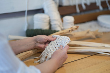 base knots of macrame, the view from behind the shoulder close-up of the women hands, she ties knots. ECO friendly modern knitting DIY natural decoration concept.の写真素材