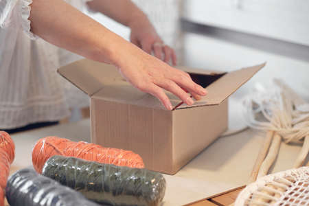 woman entrepreneur packs an order in a cardboard box to be sent by a courier company. an elderly woman created a business out of her hobby.の写真素材