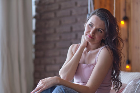 upset brunette woman sitting on the linen in bed at home. depressed woman after divorce.