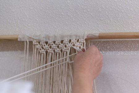 base knots of macrame, the view from behind the shoulder close-up of the women hands, she ties knots. ECO friendly modern knitting DIY natural decoration concept.の写真素材