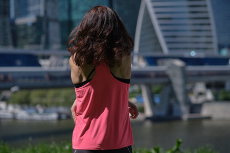 Rear view of middle age womans takes off her jersey after an intense workout and looking at a view....