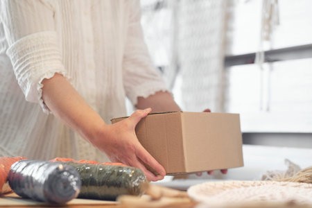 woman entrepreneur packs a handmade product in a cardboard box. delivery of goods for a small...