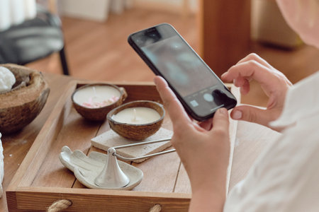 woman entrepreneur makes stylish photos on a smartphone to advertise herself on social networks. promotion in the internetの写真素材