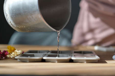 woman pours beeswax into a silicone mold to make candlesの写真素材