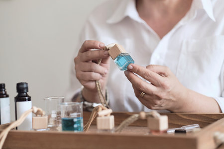 Close-up of a pipette with oil and a glass bottle. woman pouring perfume in bottle. Perfume creating workshopの写真素材