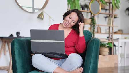 female celebrating good news. woman overjoyed get mail at laptop being promoted at work, girl amazed read good news at computerの写真素材