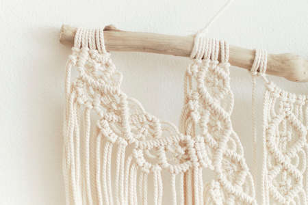 Beautiful boho macrame on wall panel. tapestry in the style of Boho made of cotton threads in natural color using the macrame technique for home decor and wedding decoration. light pastel colorsの写真素材