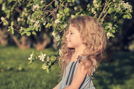 Portrait of happy little girl whith cherry tree flowers. spring bloomの写真素材